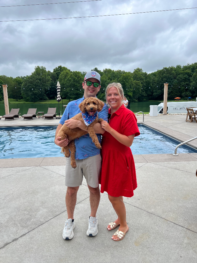 Lady, a red Goldendoodle, with her family by the pool