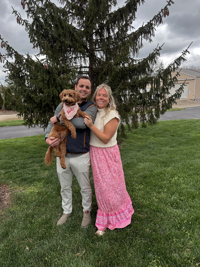 Lady, a red Goldendoodle, with her family outdoors
